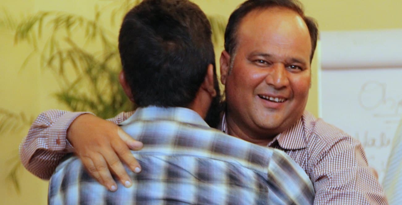 Two participants embracing at the close of a turnshop, one grinning over the other's shoulder