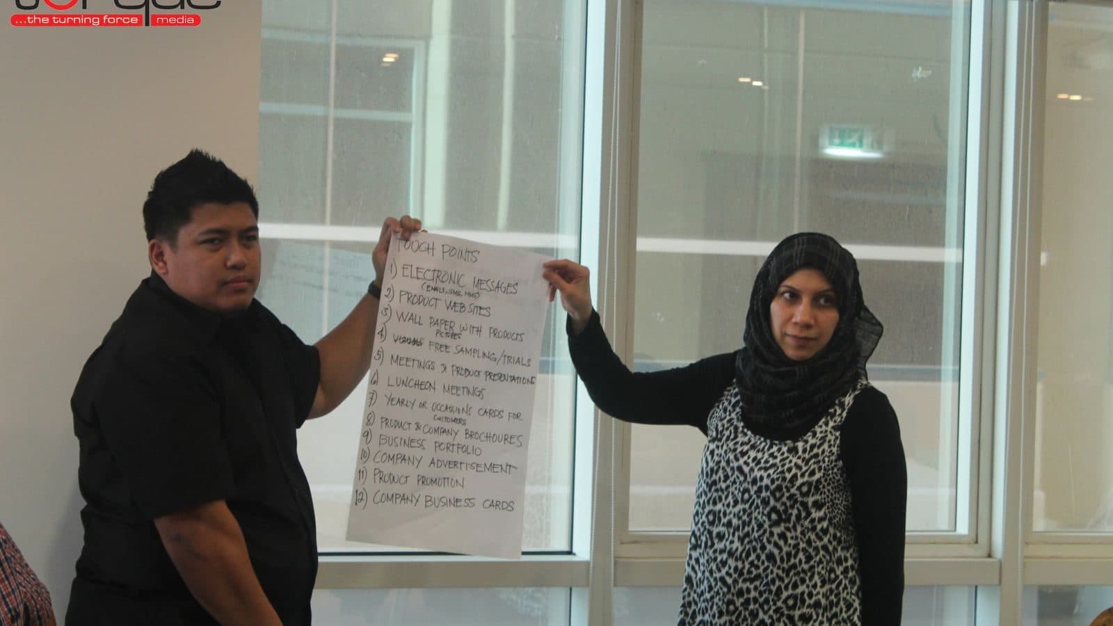 Two participants holding a flipchart sheet up between them and presenting what is written on it