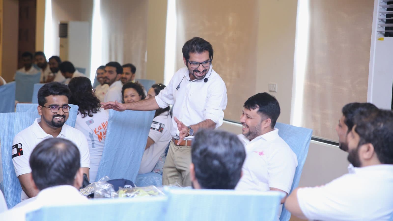 A table of participants reaching across each other mid-activity, chairs pushed back