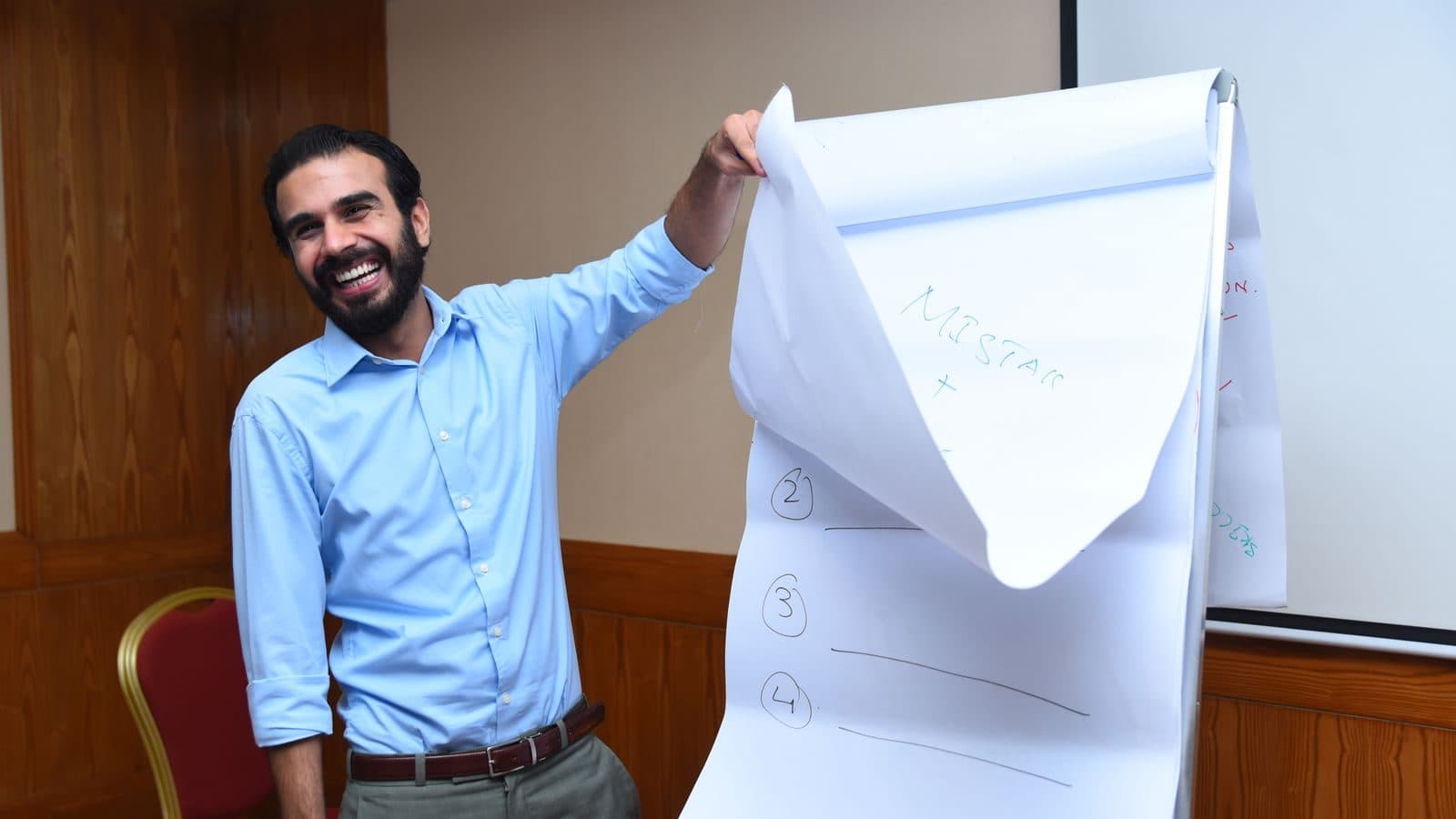 A participant grinning as he holds up the flipchart page his group has just finished
