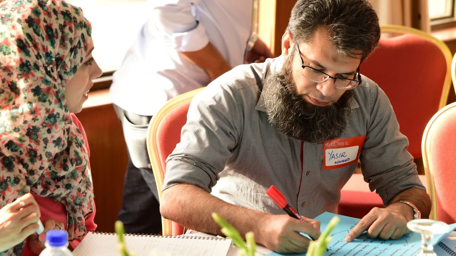A participant bent over his workbook, writing with a red marker